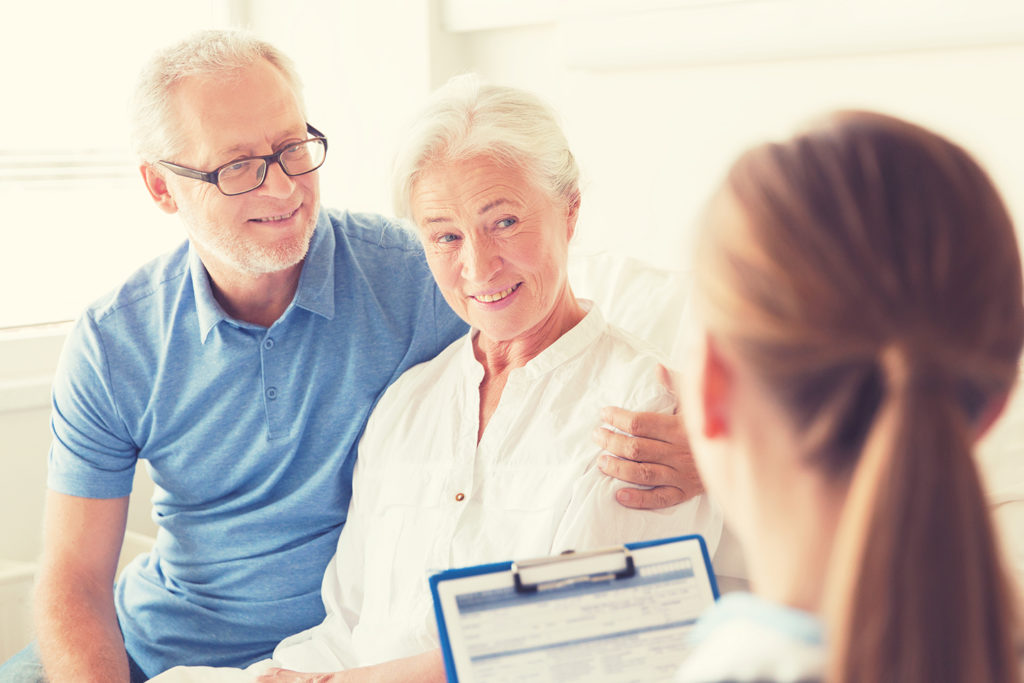 senior woman and doctor with clipboard at hospital