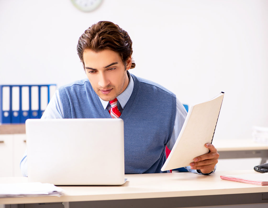 Young handsome employee working in the office