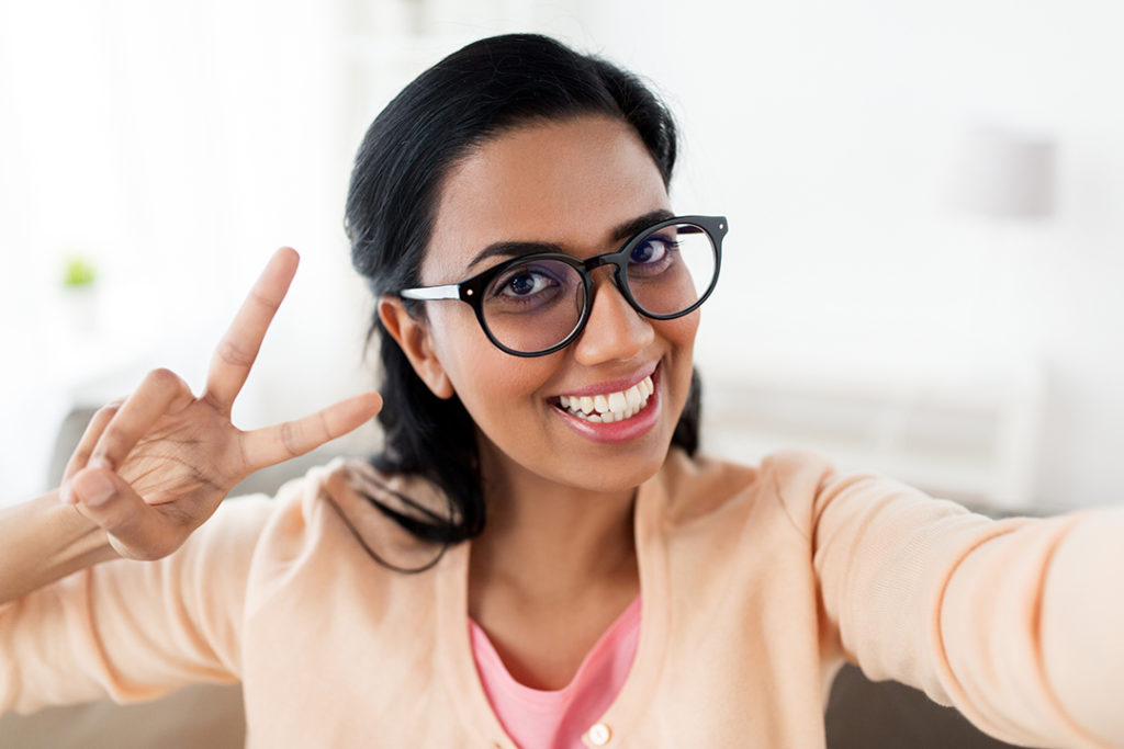 smiling woman taking selfie and showing v sign