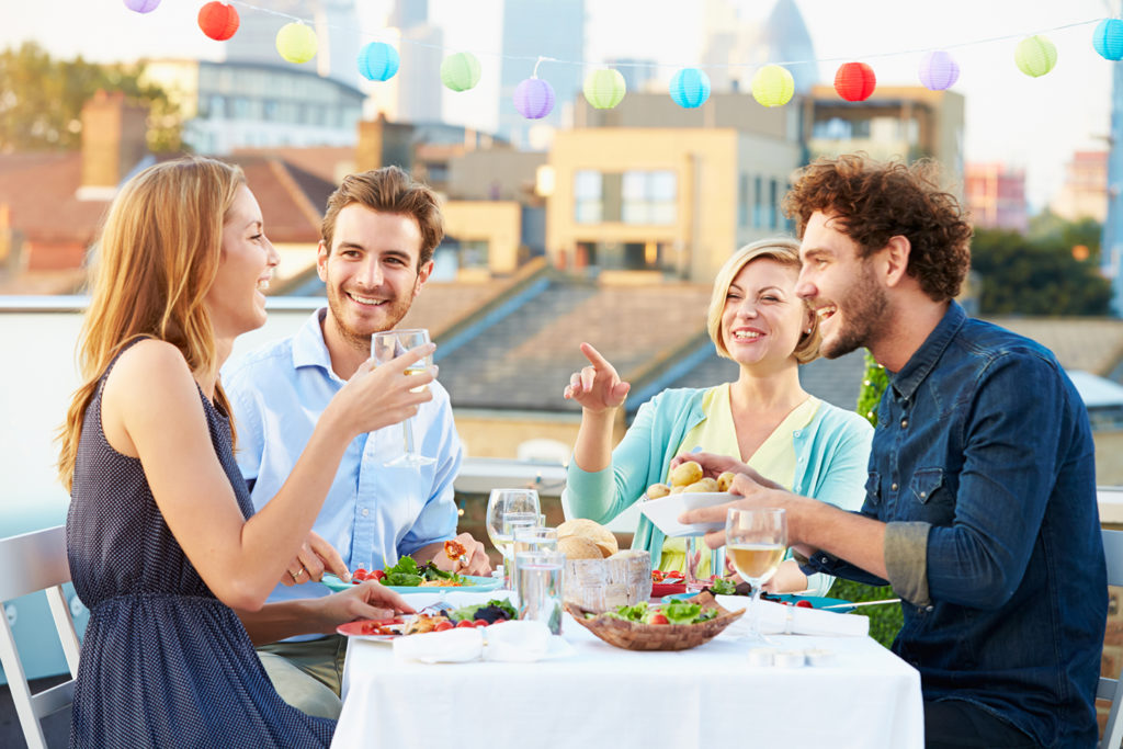 a group of friends enjoying food on a rooftop at a table