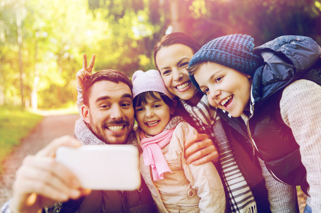 happy family taking selfie by smartphone outdoors