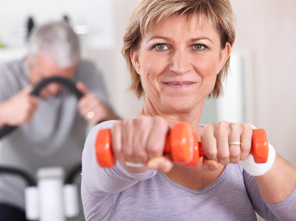 A woman with small weights in her hands and doing a workout
