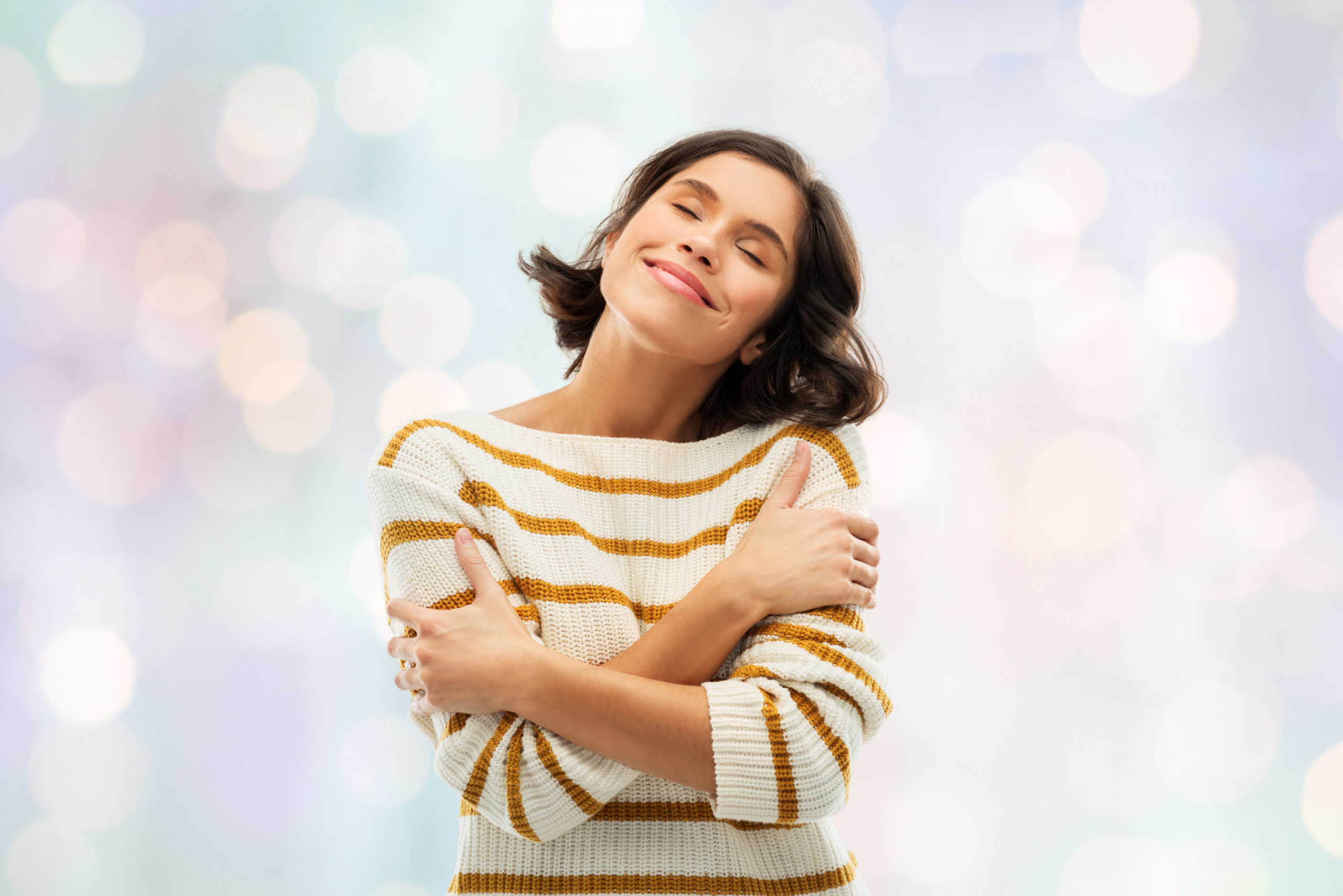 happy woman in striped pullover hugging herself