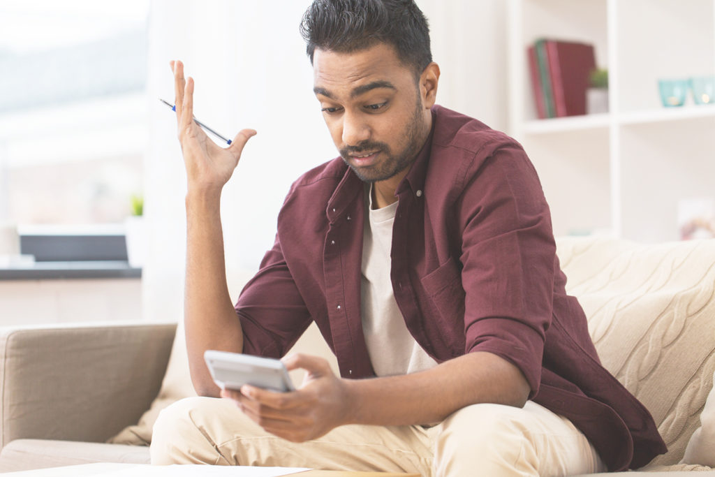 confused man with calculator at home