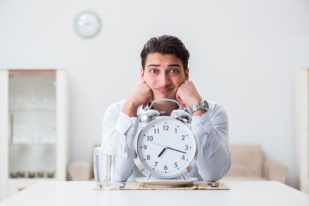 A man waiting with a an alarm clock