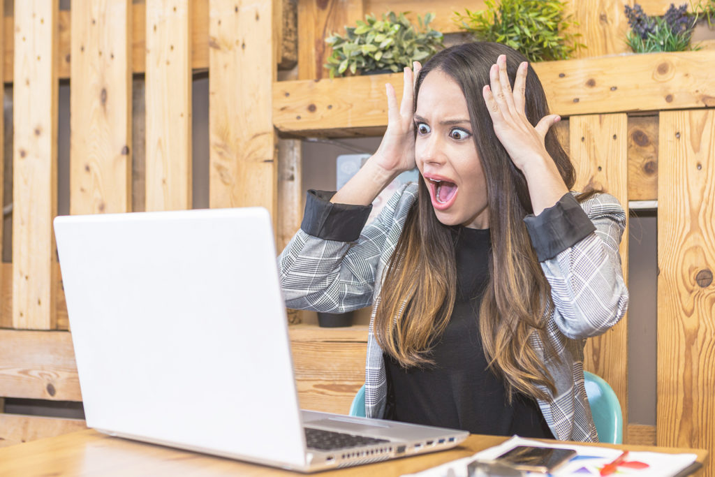 Woman reading shocking information on laptop screen