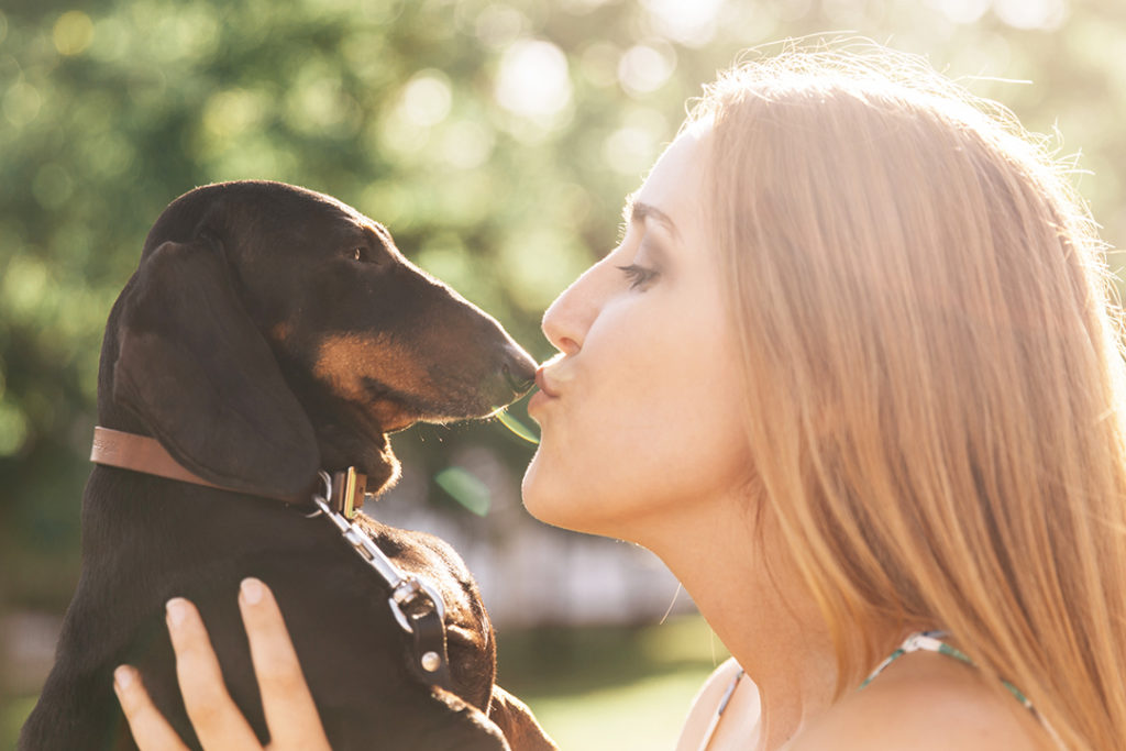 side view beautiful young woman kissing her dog