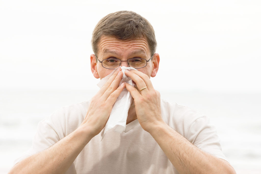 A man blowing his nose with a cold caused by germs