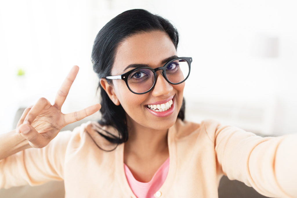 smiling woman taking selfie and showing v sign