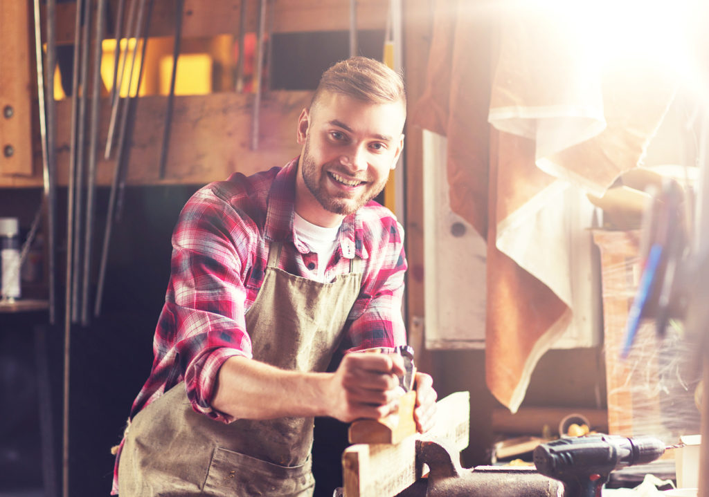 carpenter working with plane and wood at workshop