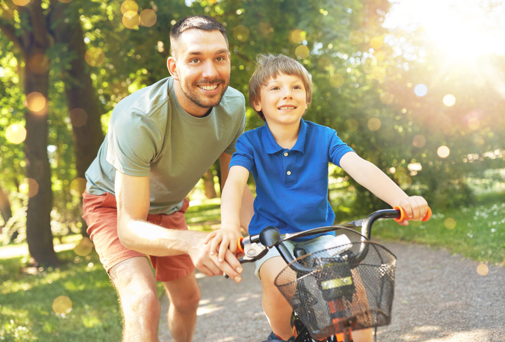 Father teaching little son to ride bicycle at park