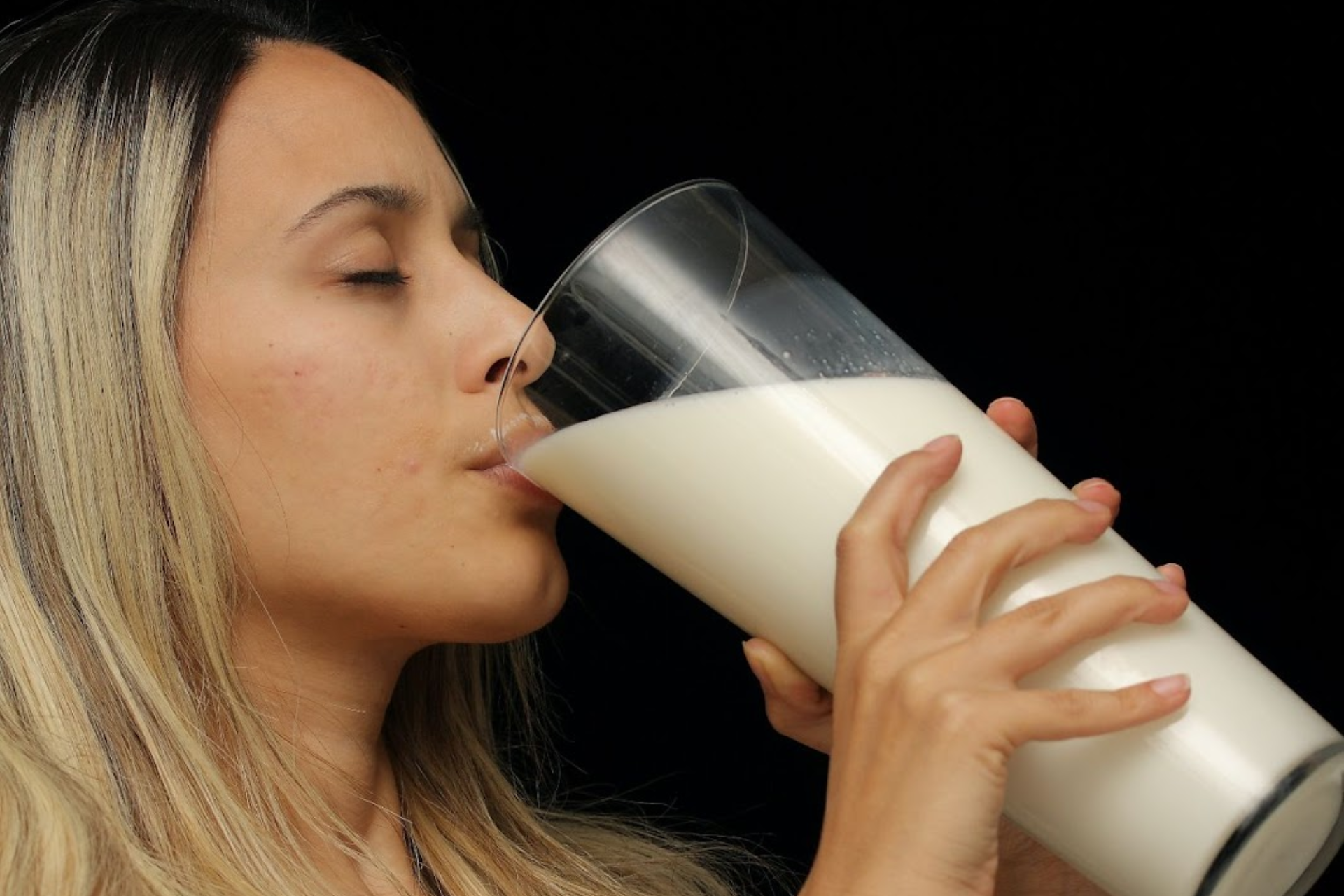 A woman drinking a large glass of milk